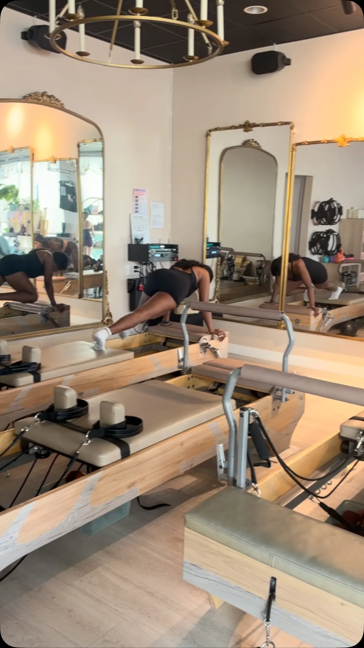 A reformer class holding a plank in the bright studio, gold-framed mirrors along the wall
