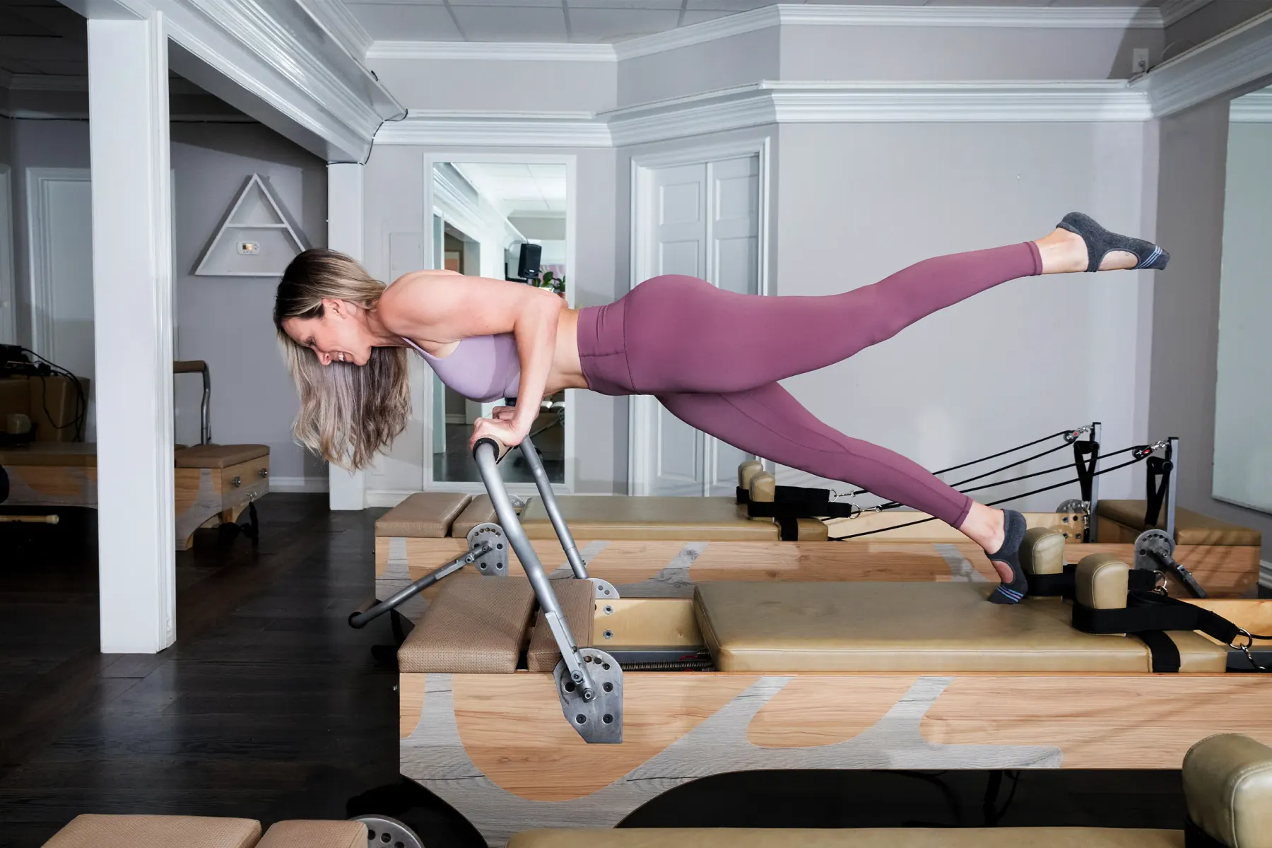 An instructor coaching a client through a standing reformer exercise